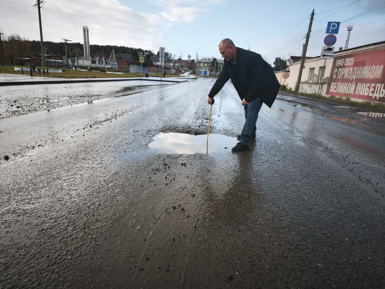 Начальник аварийно-спасательной службы Сергей Слученков измеряет размер ям на дорогах Кирзавода. Все разрушения здесь — исключительно по вине тяжелого транспорта, который в огромном количестве ездил по Ревде во время ремонта федеральной трассы. Фото Ольги Вертлюговой