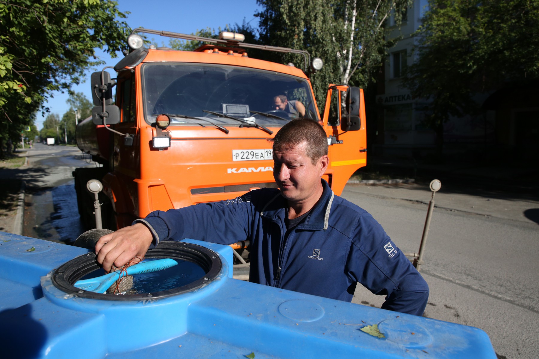 Николай Кукушкин соединяет бак трактора с цистерной поливомоечной машины, чтобы та поделилась своими запасами воды. Фото Владимира Коцюбы-Белых