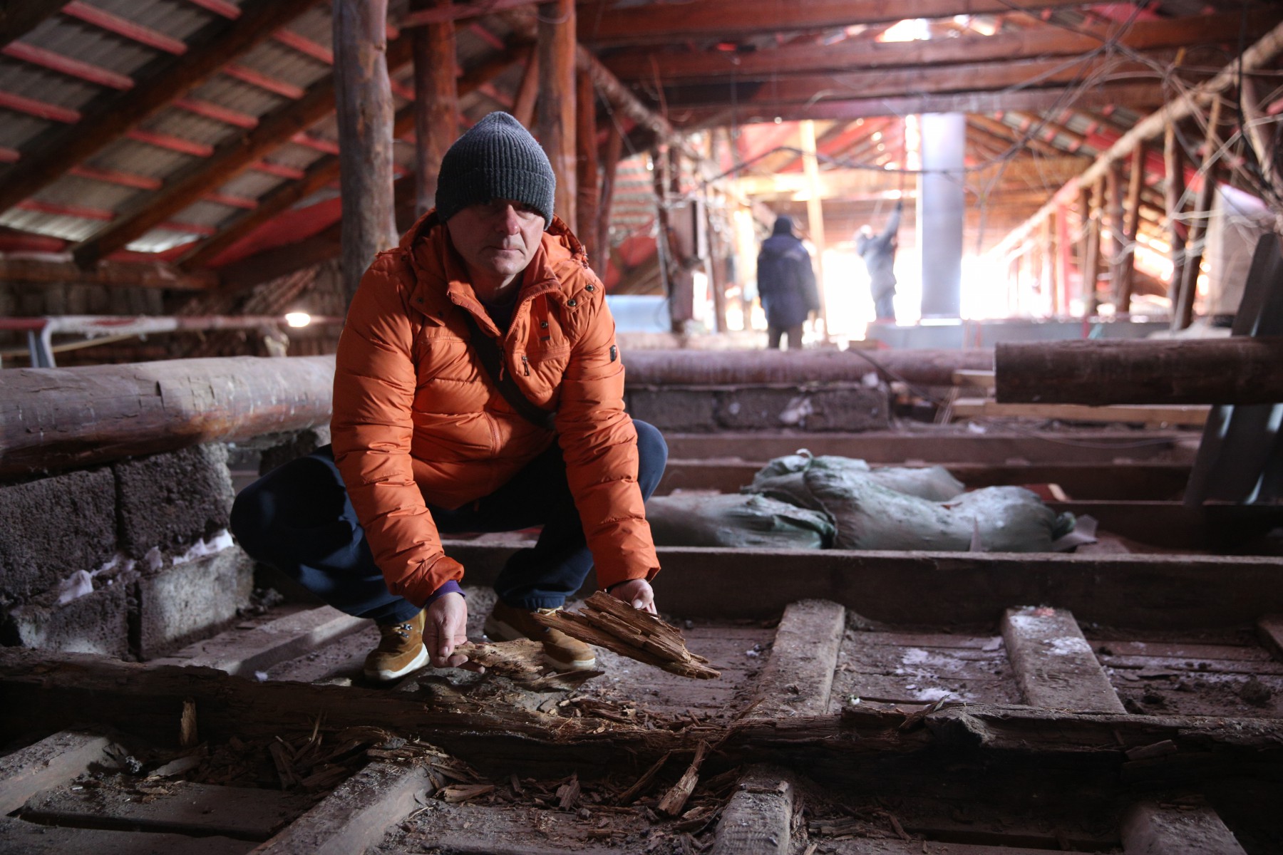 Дмитрий Заколюкин показывает, что балки чердака сгнили из-за постоянной влаги. Фото Владимира Коцюбы-Белых