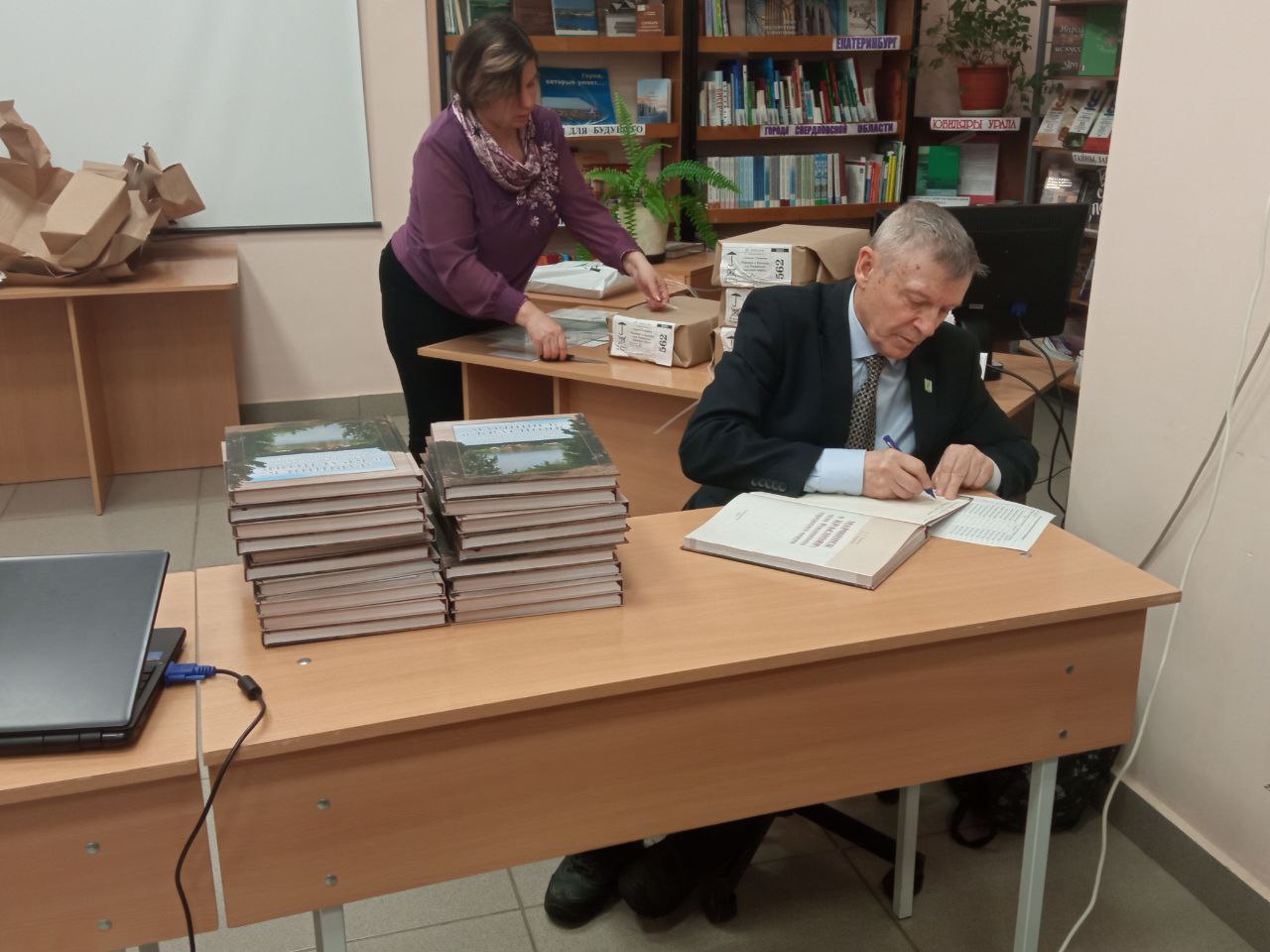 Сергей Новиков подписывает экземпляры своей книги для участников ее презентации. Фото из архива редакции